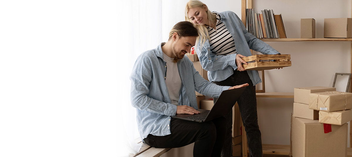 Young couple moving to a new home relaxing sitting using computer laptop, smiling happy for moving to new apartment